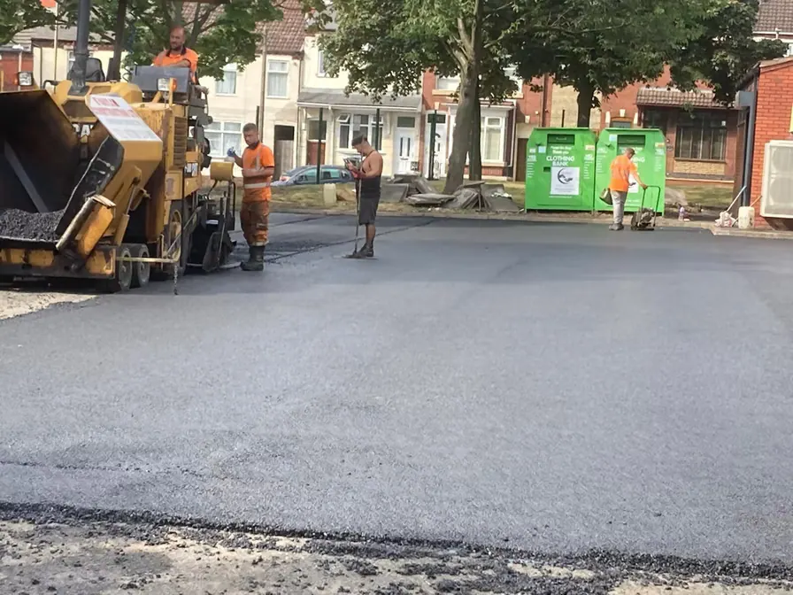 Paving machine laying tarmac outside homes